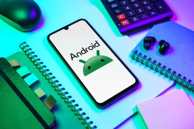 Prag, Çek Cumhuriyeti - 08 18 2025: Merkezde Android logosunu gösteren bir cep telefonu ile ofis malzemeleri düzenlemesi. Android akıllı telefonlar ve tabletler için mobil bir işletim sistemidir..