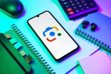 Prag, Çek Cumhuriyeti - 08 18 2025: Merkezde Google Lens logosunu gösteren bir cep telefonu ile ofis malzemeleri düzenlemesi. Google Lens, resimlerdeki görsel arama ve bilgi için kullanılan bir araçtır..