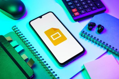 Prag, Çek Cumhuriyeti - 08 18 2025: Merkezde Google Slides logosunu gösteren bir cep telefonu ile ofis malzemeleri düzenlemesi. Google Slides sunumlar ve slayt gösterileri oluşturmak için bir platformdur.