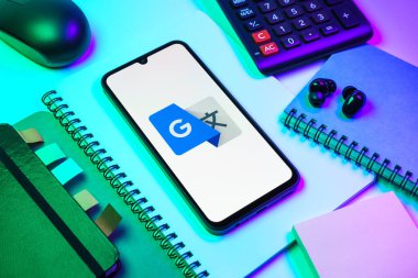 Prag, Çek Cumhuriyeti - 08 18 2025: Merkezde Google Translate logosunu gösteren bir cep telefonu ile ofis malzemeleri düzenlemesi. Google Çevirisi metni ve konuşmayı diller arası çevirmek için bir platformdur..