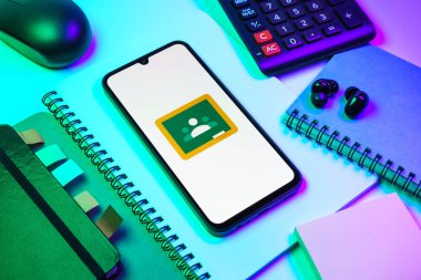 Prag, Çek Cumhuriyeti - 08 18 2025: Merkezde Google Sınıfı logosunu gösteren bir cep telefonu ile ofis malzemeleri düzenlemesi. Google Sınıfı, sınıfları ve eğitim içeriğini yönetmek için bir platformdur.