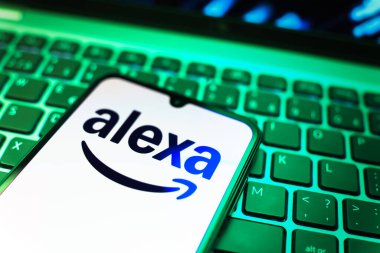 Prag, Çek Cumhuriyeti - 08 19 2025: Klavyenin üzerinde Alexa logosunu gösteren cep telefonunun yakın çekim görüntüsü. Alexa akıllı aygıtlar ve servisler için ses asistanıdır.