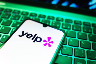 Prag, Çek Cumhuriyeti - 08 19 2025: Klavyede duran ve Yelp logosunu gösteren bir cep telefonunun yakından görüntüsü. Yelp yerel işletmeleri bulmak ve incelemek için bir platformdur.