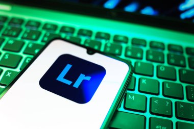 Prag, Çek Cumhuriyeti - 08 19 2025: Klavyede duran ve Lightroom logosunu gösteren cep telefonunun yakından görüntüsü. Lightroom fotoğraf düzenleme ve yönetim için bir yazılımdır..