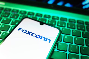 Prag, Çek Cumhuriyeti - 08 19 2025: Foxconn logosunu gösteren klavyenin üzerinde duran cep telefonunun yakından görüntüsü. Foxconn elektronik ve parça üreten bir şirket..