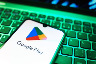 Prag, Çek Cumhuriyeti - 08 19 2025: Google Play logosunu gösteren klavyenin üzerinde duran bir cep telefonunun yakından görüntüsü. Google Play uygulamaları, oyunları ve dijital içeriği indirmek için bir platformdur.