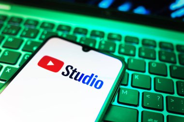 Prag, Çek Cumhuriyeti - 08 19 2025: Youtube Stüdyo logosunu gösteren klavyenin üzerinde duran cep telefonunun yakından görüntüsü. Youtube Studio YouTube kanallarını yönetmek ve analiz etmek için bir platformdur.