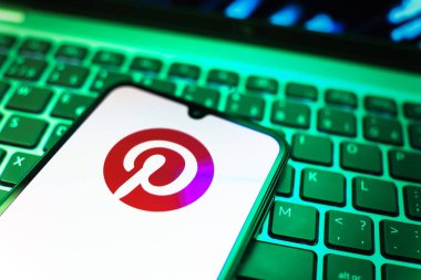 Prag, Çek Cumhuriyeti - 08 19 2025: Pinterest logosunu gösteren klavyenin üzerinde duran cep telefonunun yakından görüntüsü. Pinterest fikirleri görsel olarak keşfetmek ve kaydetmek için bir platformdur..