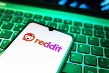 Prag, Çek Cumhuriyeti - 08 19 2025: Bir klavyenin üzerinde duran ve Reddit logosunu gösteren cep telefonunun yakından görüntüsü. Reddit tartışma, haber ve toplum içeriği için bir platformdur.