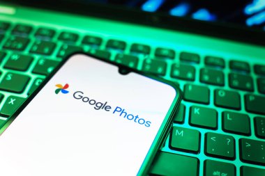Prag, Çek Cumhuriyeti - 08 19 2025: Google Photos logosunu gösteren klavyenin üzerinde duran cep telefonunun yakından görüntüsü. Google Fotoğrafları fotoğraf ve videoları saklamak ve düzenlemek için bir platformdur.
