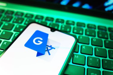 Prag, Çek Cumhuriyeti - 08 19 2025: Google Translate logosunu gösteren klavyenin üzerinde duran cep telefonunun yakından görüntüsü. Google Çevirisi metni ve konuşmayı diller arası çevirmek için bir platformdur..
