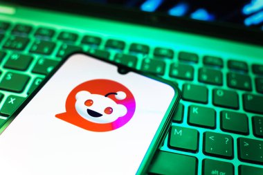 Prag, Çek Cumhuriyeti - 08 19 2025: Bir klavyenin üzerinde duran ve Reddit logosunu gösteren cep telefonunun yakından görüntüsü. Reddit tartışma, haber ve toplum içeriği için bir platformdur.