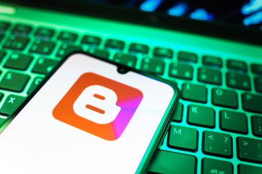 Prag, Çek Cumhuriyeti - 08 19 2025: Klavyenin üzerinde duran ve Blogger logosunu gösteren cep telefonunun yakından görüntüsü. Blogger blog oluşturma ve yayınlama için bir platformdur.