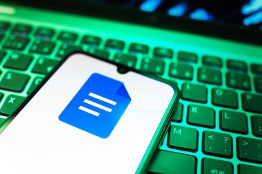 Prag, Çek Cumhuriyeti - 08 19 2025: Google Docs logosunu gösteren klavyenin üzerinde duran cep telefonunun yakından görüntüsü. Google Docs metin belgeleri oluşturmak ve düzenlemek için bir platformdur.