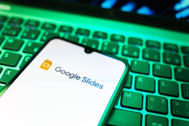 Prag, Çek Cumhuriyeti - 08 19 2025: Google Slides logosunu gösteren klavyenin üzerinde duran cep telefonunun yakından görüntüsü. Google Slides sunumlar ve slayt gösterileri oluşturmak için bir platformdur.
