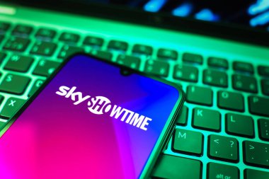 Prag, Çek Cumhuriyeti - 08 19 2025: SkyShowtime logosunu gösteren klavyenin üzerinde duran cep telefonunun yakından görüntüsü. SkyShowtime, sinema ve televizyon dizileri için bir yayın platformudur..
