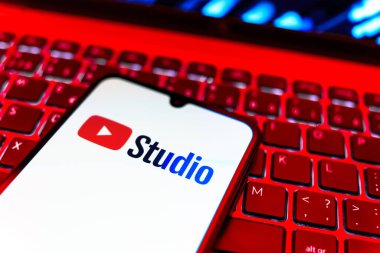Prag, Çek Cumhuriyeti - 08 19 2025: Youtube Stüdyo logosunu gösteren klavyenin üzerinde duran cep telefonunun yakından görüntüsü. Youtube Studio YouTube kanallarını yönetmek ve analiz etmek için bir platformdur.
