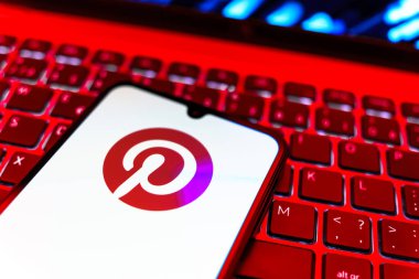 Prag, Çek Cumhuriyeti - 08 19 2025: Pinterest logosunu gösteren klavyenin üzerinde duran cep telefonunun yakından görüntüsü. Pinterest fikirleri görsel olarak keşfetmek ve kaydetmek için bir platformdur..