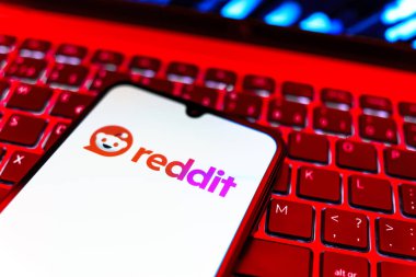 Prag, Çek Cumhuriyeti - 08 19 2025: Bir klavyenin üzerinde duran ve Reddit logosunu gösteren cep telefonunun yakından görüntüsü. Reddit tartışma, haber ve toplum içeriği için bir platformdur.