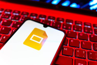 Prag, Çek Cumhuriyeti - 08 19 2025: Google Slides logosunu gösteren klavyenin üzerinde duran cep telefonunun yakından görüntüsü. Google Slides sunumlar ve slayt gösterileri oluşturmak için bir platformdur.