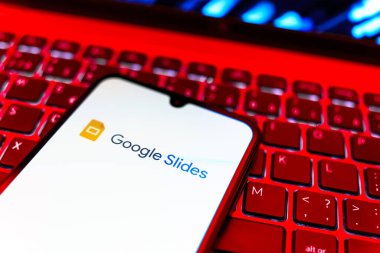 Prag, Çek Cumhuriyeti - 08 19 2025: Google Slides logosunu gösteren klavyenin üzerinde duran cep telefonunun yakından görüntüsü. Google Slides sunumlar ve slayt gösterileri oluşturmak için bir platformdur.