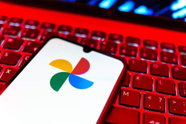 Prag, Çek Cumhuriyeti - 08 19 2025: Google Photos logosunu gösteren klavyenin üzerinde duran cep telefonunun yakından görüntüsü. Google Fotoğrafları fotoğraf ve videoları saklamak ve düzenlemek için bir platformdur.