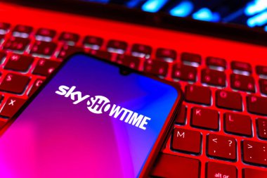 Prag, Çek Cumhuriyeti - 08 19 2025: SkyShowtime logosunu gösteren klavyenin üzerinde duran cep telefonunun yakından görüntüsü. SkyShowtime, sinema ve televizyon dizileri için bir yayın platformudur..