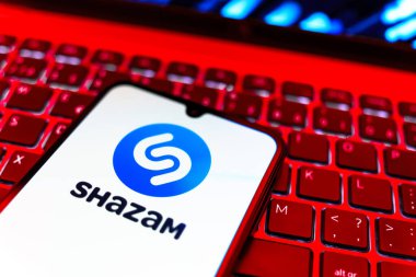Prag, Çek Cumhuriyeti - 08 19 2025: Klavyede duran ve Shazam logosunu gösteren bir cep telefonunun yakından görüntüsü. Shazam şarkıları ve müzik parçalarını tanımlamak için bir uygulamadır.