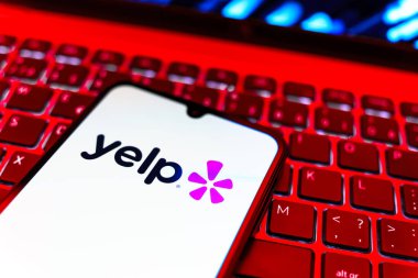 Prag, Çek Cumhuriyeti - 08 19 2025: Klavyede duran ve Yelp logosunu gösteren bir cep telefonunun yakından görüntüsü. Yelp yerel işletmeleri bulmak ve incelemek için bir platformdur.