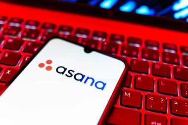 Prag, Çek Cumhuriyeti - 08 19 2025: Klavyede duran ve Asana logosunu gösteren cep telefonunun yakından görüntüsü. Asana görev yönetimi ve takım işbirliği için bir platformdur..