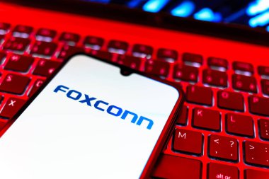 Prag, Çek Cumhuriyeti - 08 19 2025: Foxconn logosunu gösteren klavyenin üzerinde duran cep telefonunun yakından görüntüsü. Foxconn elektronik ve parça üreten bir şirket..