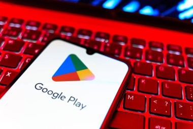 Prag, Çek Cumhuriyeti - 08 19 2025: Google Play logosunu gösteren klavyenin üzerinde duran bir cep telefonunun yakından görüntüsü. Google Play uygulamaları, oyunları ve dijital içeriği indirmek için bir platformdur.