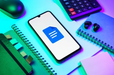 Prag, Çek Cumhuriyeti - 08 18 2025: Merkezde Google Docs logosunu gösteren bir cep telefonu ile ofis malzemeleri düzenlemesi. Google Docs metin belgeleri oluşturmak ve düzenlemek için bir platformdur.