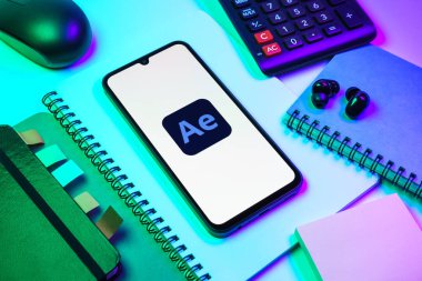 Prag, Çek Cumhuriyeti - 08 18 2025: Ofis malzemelerinin merkezde After Effects logosu sergilenen bir cep telefonu ile düzenlenmesi. After Effects hareket grafikleri ve görsel efektler için bir yazılımdır..