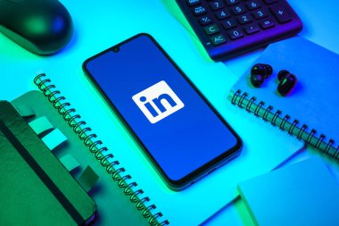 Prag, Çek Cumhuriyeti - 08 18 2025: Merkezde LinkedIn logosunu gösteren bir cep telefonu ile ofis malzemeleri düzenlemesi. LinkedIn, insanları ve şirketleri birbirine bağlayan profesyonel bir ağ..