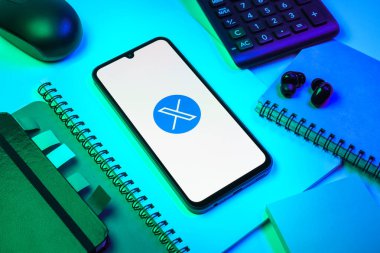 Prag, Çek Cumhuriyeti - 08 18 2025: Merkezinde X logosu sergilenen bir cep telefonu ile ofis malzemeleri düzenlemesi. X, kısa gönderileri ve güncellemeleri paylaşmak için bir platformdur.