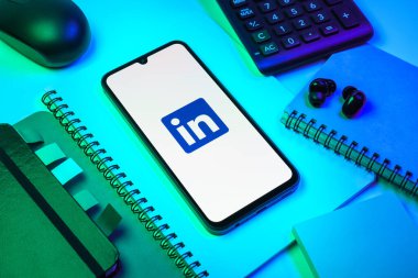 Prag, Çek Cumhuriyeti - 08 18 2025: Merkezde LinkedIn logosunu gösteren bir cep telefonu ile ofis malzemeleri düzenlemesi. LinkedIn, insanları ve şirketleri birbirine bağlayan profesyonel bir ağ..