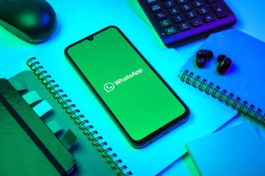 Prag, Çek Cumhuriyeti - 08 18 2025: Ofis malzemelerinin merkezde WhatsApp logosunu gösteren bir cep telefonu ile düzenlenmesi. WhatsApp mesaj, çağrı ve medya göndermek için bir uygulamadır.