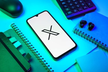 Prag, Çek Cumhuriyeti - 08 18 2025: Merkezinde X logosu sergilenen bir cep telefonu ile ofis malzemeleri düzenlemesi. X, kısa gönderileri ve güncellemeleri paylaşmak için bir platformdur.