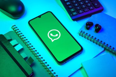 Prag, Çek Cumhuriyeti - 08 18 2025: Ofis malzemelerinin merkezde WhatsApp logosunu gösteren bir cep telefonu ile düzenlenmesi. WhatsApp mesaj, çağrı ve medya göndermek için bir uygulamadır.