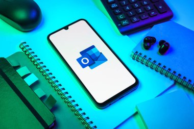 Prag, Çek Cumhuriyeti - 08 18 2025: Merkezde Outlook logosunu gösteren bir cep telefonu ile ofis malzemeleri düzenlemesi. Outlook iletileri göndermek ve yönetmek için bir e- posta platformudur.
