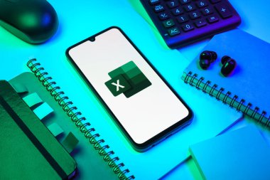 Prag, Çek Cumhuriyeti - 08 18 2025: Excel logosu sergilenen bir cep telefonu ile ofis malzemeleri düzenlemesi. Excel, tablo, veri analizi ve hesaplamalar için bir yazılımdır..