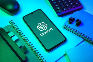 Prag, Çek Cumhuriyeti - 08 18 2025: Merkezinde ChatGPT logosu bulunan bir cep telefonu ile ofis malzemeleri düzenlemesi. ChatGPT metin üretmek ve soruları cevaplamak için bir yapay zeka sohbet robotudur..