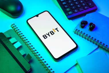 Prag, Çek Cumhuriyeti - 08 18 2025: Merkezde Bybit logosunu gösteren bir cep telefonu ile ofis malzemeleri düzenlemesi. Bybit şifreli para ve türev ticareti için bir platformdur.