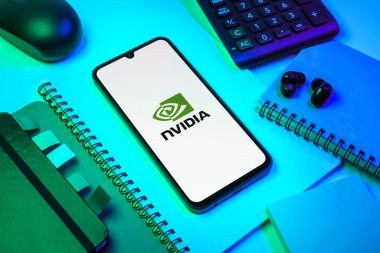 Prag, Çek Cumhuriyeti - 08 18 2025: Merkezinde NVIDIA logosu bulunan bir cep telefonu ile ofis malzemeleri düzenlemesi. NVIDIA, GPU ve yapay zeka donanımı alanında uzmanlaşmış bir teknoloji şirketidir..