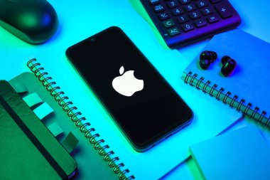 Prag, Çek Cumhuriyeti - 08 18 2025: Merkezi Apple logosunu gösteren bir cep telefonu ile ofis malzemeleri düzenlemesi. Apple iPhone, bilgisayar ve hizmet üreten bir teknoloji şirketidir..