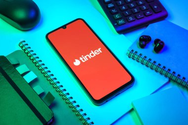 Prag, Çek Cumhuriyeti - 08 18 2025: Merkezde Tinder logosu sergilenen bir cep telefonu ile ofis malzemeleri düzenlemesi. Tinder insanları eşleştirmek ve bağlamak için bir randevu uygulaması.