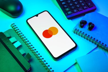 Prag, Çek Cumhuriyeti - 08 18 2025: Merkezde Mastercard logosu sergilenen bir cep telefonu ile ofis malzemeleri düzenlemesi. Mastercard ödeme kartları ve hizmetler sağlayan bir finans şirketidir..