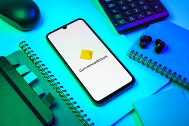 Prag, Çek Cumhuriyeti - 08 18 2025: Merkezinde Commonwealth Bank logosu bulunan bir cep telefonu ile ofis malzemeleri düzenlemesi. Commonwealth Bank, Avustralya 'da finansal hizmetler sağlayan bir bankadır..