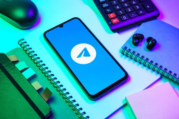 Prag, Çek Cumhuriyeti - 08 18 2025: Merkezde Telegram logosunu gösteren bir cep telefonu ile ofis malzemeleri düzenlemesi. Telgraf hızlı ve güvenli iletiler için bir uygulamadır.